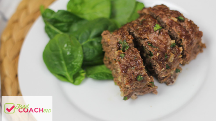 Low carb meatloaf beef and onion with chopped spinach on a white plate