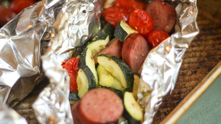 Turkey Sausage and Veggies foil packets with turkey kielbasa sausage zucchini and cherry tomatoes in foil on the grill